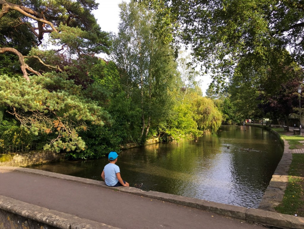 A boy watches the River Windrush drift by. ©Laurel Kallenbach